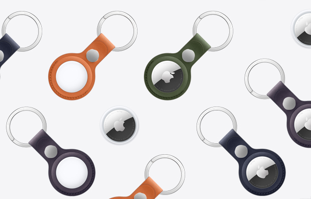 Um conjunto de AirTags com alguns presos ao chaveiros de tecido FineWoven em várias cores, incluindo laranja, verde-escuro, azul-intenso, amora-preta e preto