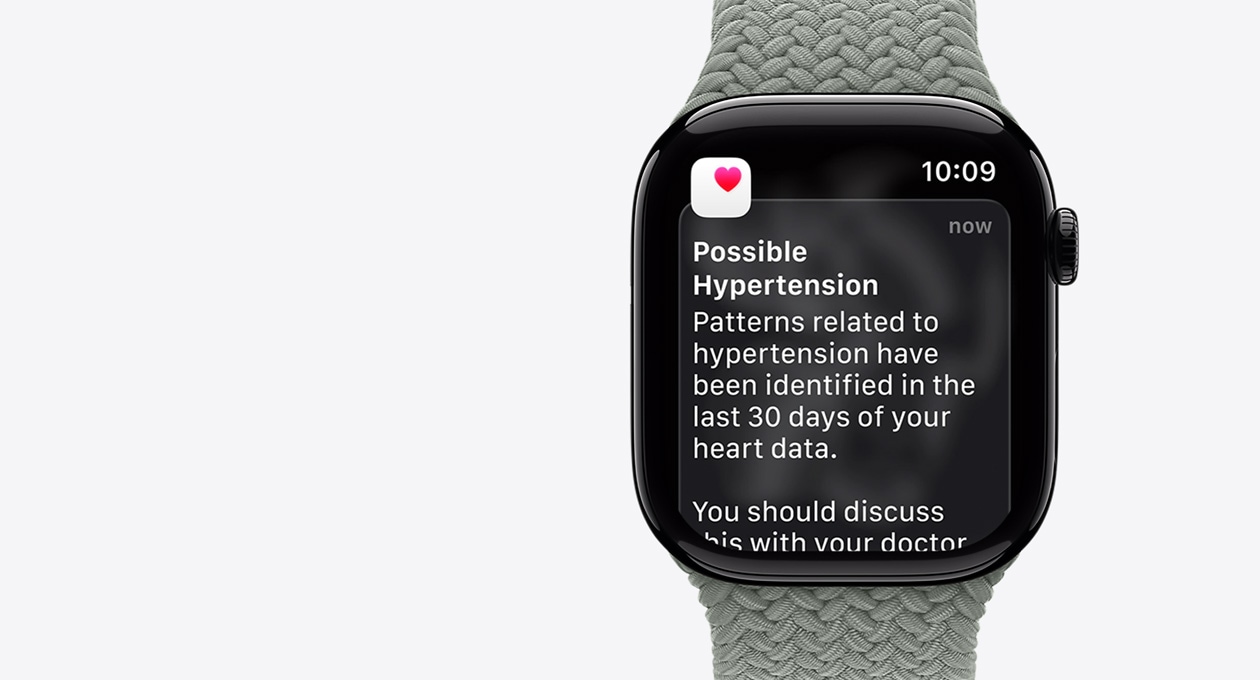 Apple Watch Series 11, φυσικό χρώμα, κάσα αλουμινίου, ειδοποίηση πιθανής υπέρτασης, ροζ καρδιά σε λευκό κουτί, εξωτερική δεξιά πλαϊνή όψη, Digital Crown, λουράκι, πράσινο γκρι Braided Solo Loop